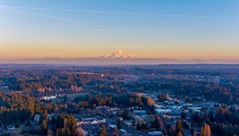 A cityscape with a mountain in the distance during sunset.