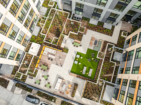A top-down view of a courtyard surrounded by buildings with a car parked on the left side.