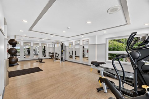 A spacious gym with wooden floors and a variety of exercise equipment.