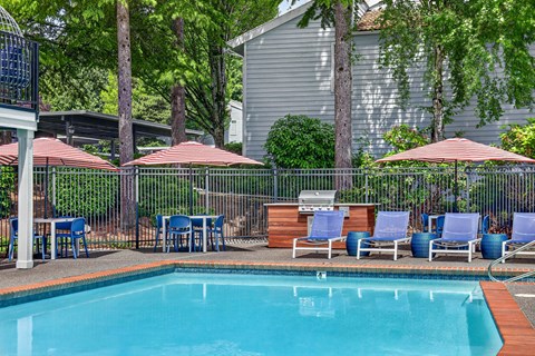 A pool surrounded by chairs and umbrellas.