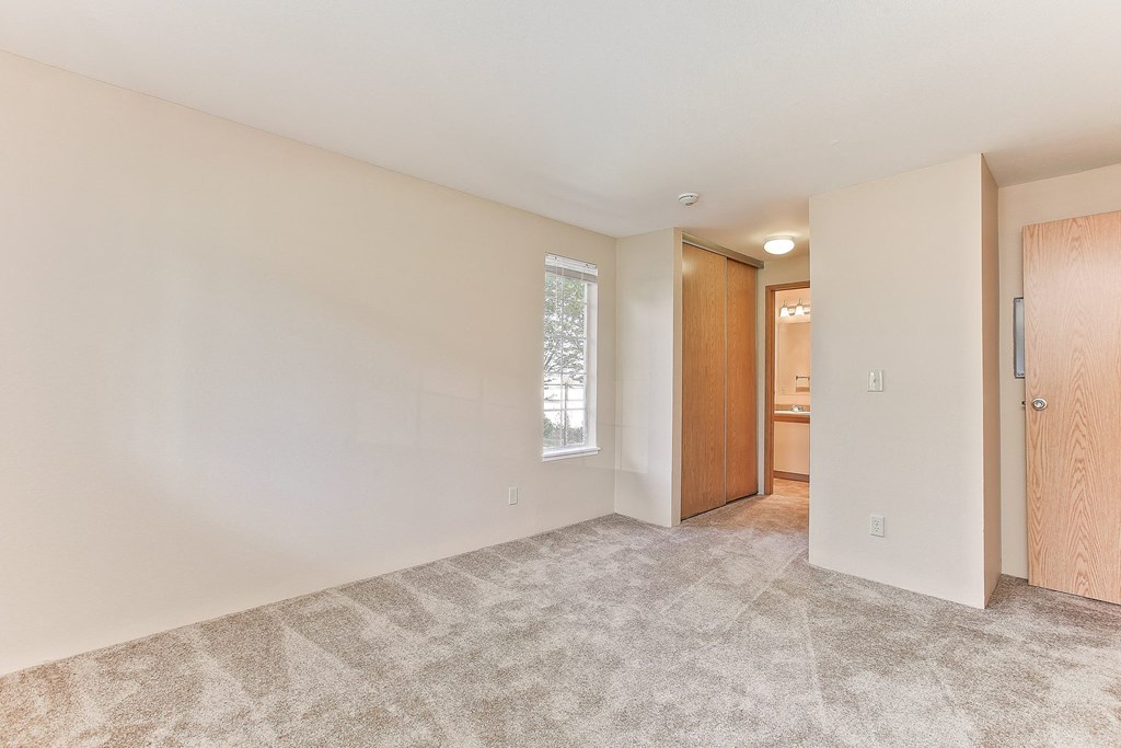 a spacious living room with carpet and a door to a bathroom