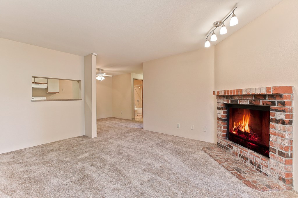 an empty living room with a fireplace and a carpeted floor