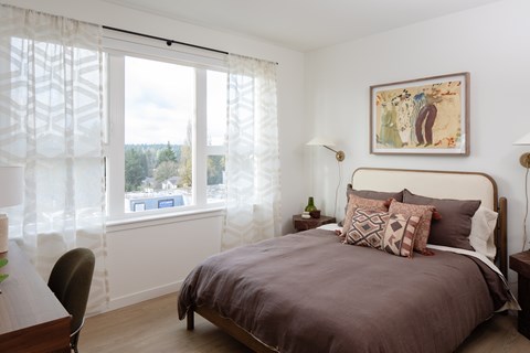 A bedroom with a large bed and a painting on the wall.