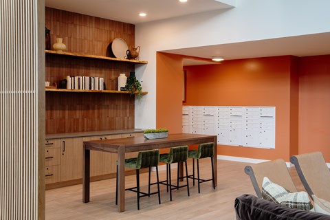 A kitchen with a table and chairs in the foreground and a calendar on the wall in the background.