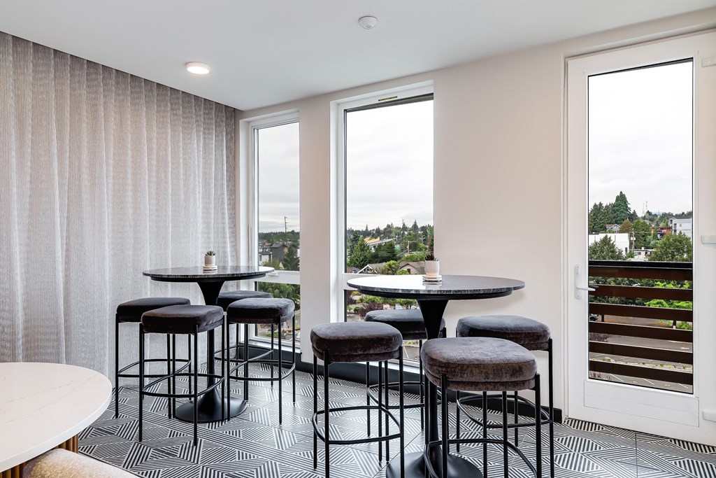 a seating area with tables and chairs in front of a window