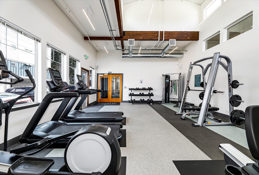 a gym with treadmills and other exercise equipment in a building with windows