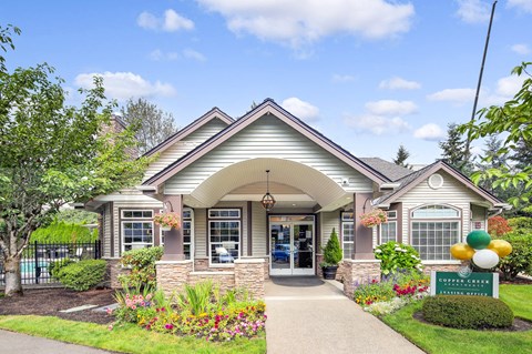 the front of a house with flowers and a sidewalk