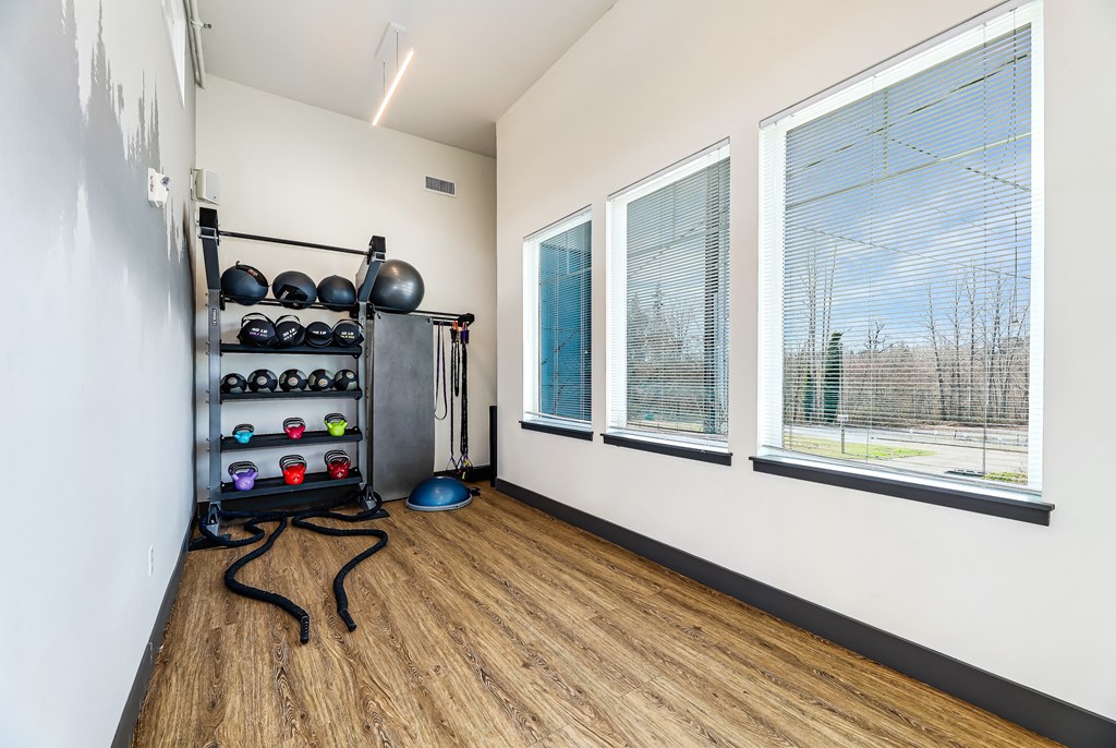 a workout room with three windows and a wood floor