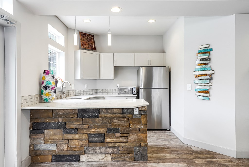 a kitchen with a stone island and stainless steel refrigerator