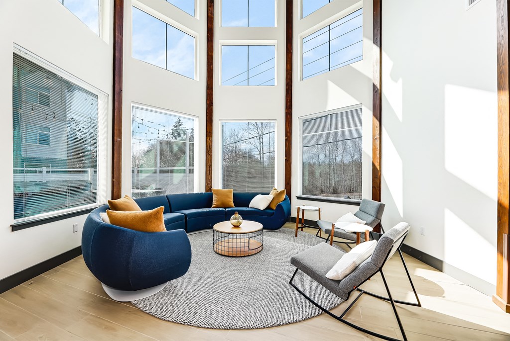 a living room with a blue couch and chairs and large windows