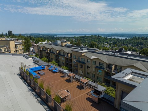 A view of a rooftop with a pool and a few chairs.
