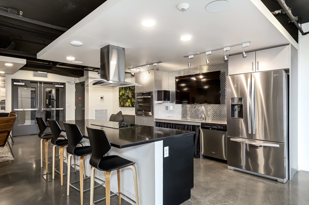 a kitchen with stainless steel appliances and a bar with chairs