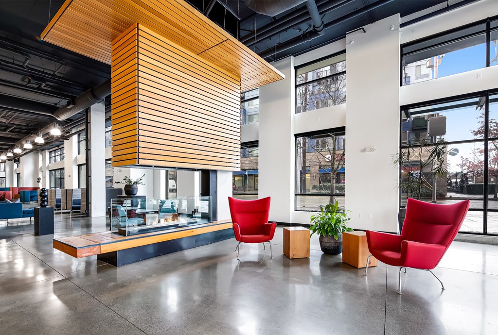 the lobby of an office building with red chairs and a large window