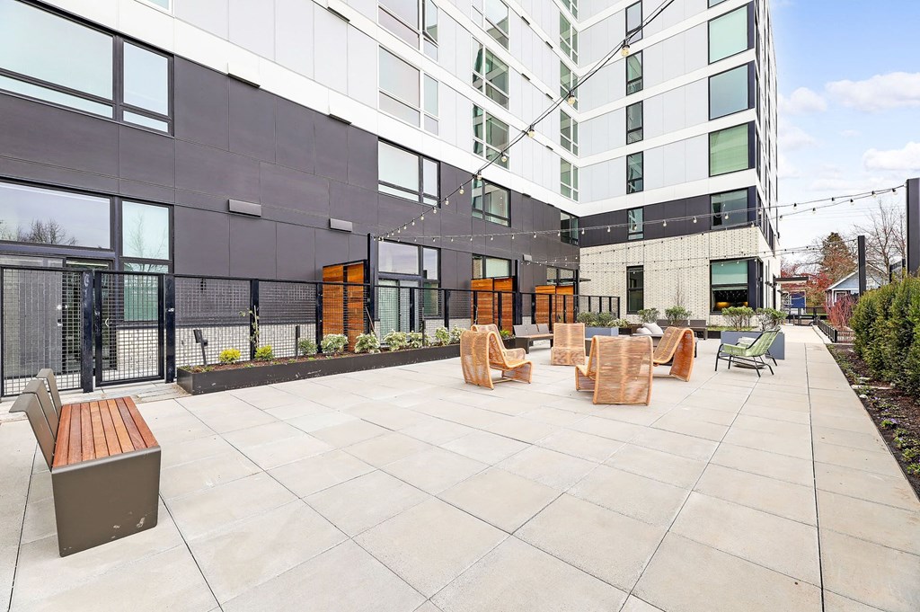 an outdoor patio with wooden benches and chairs in front of a building