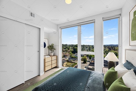 A bedroom with a large bed and a view of the outside through the windows.