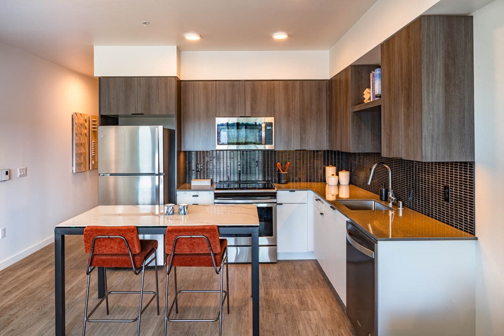 a kitchen with stainless steel appliances and a counter with chairs