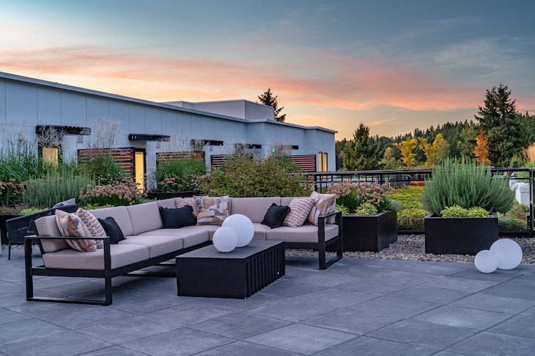 a patio with couches and chairs and a sunset in the background