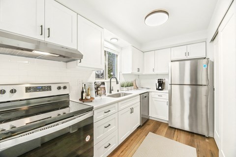a white kitchen with stainless steel appliances and white cabinets