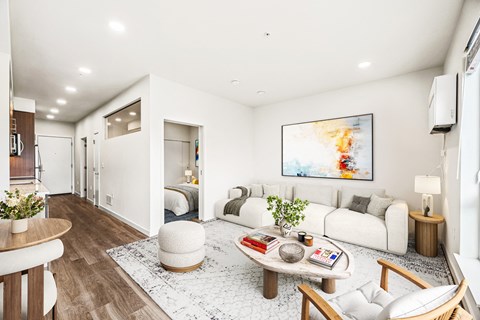 A modern living room with a white couch, a coffee table, and a painting on the wall.