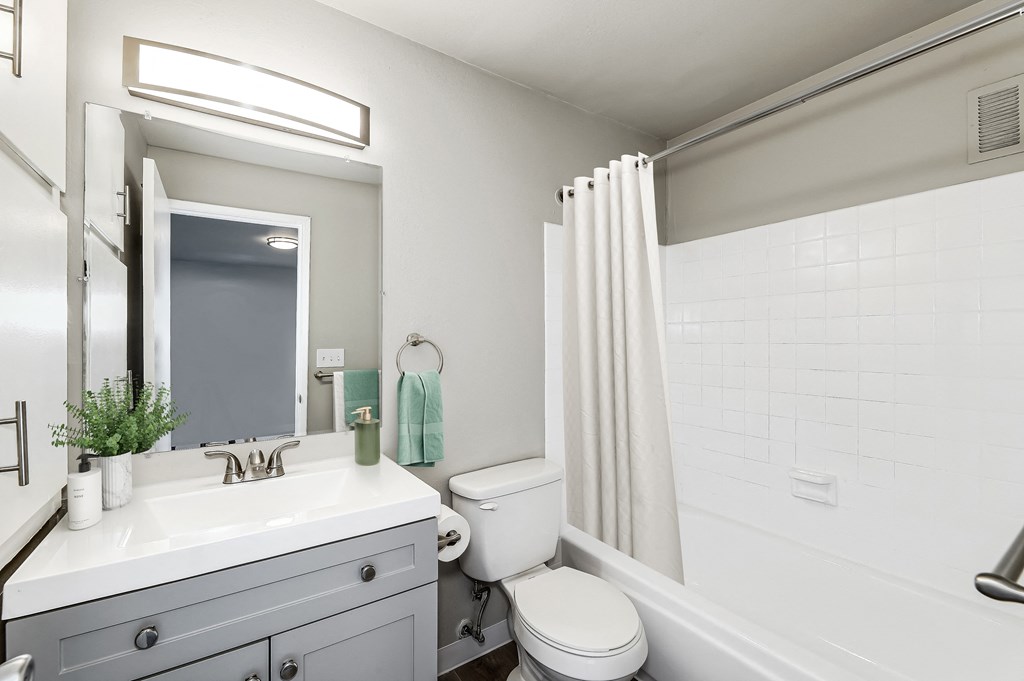 a bathroom with a white sink and toilet next to a white bathtub with a shower curtain