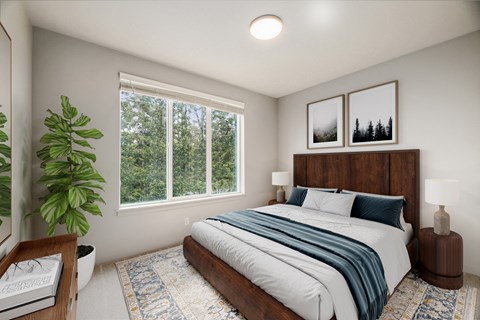 A bedroom with a large bed and a window overlooking a forest.