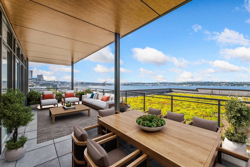 a terrace with a wooden table and chairs and a view of a body of water