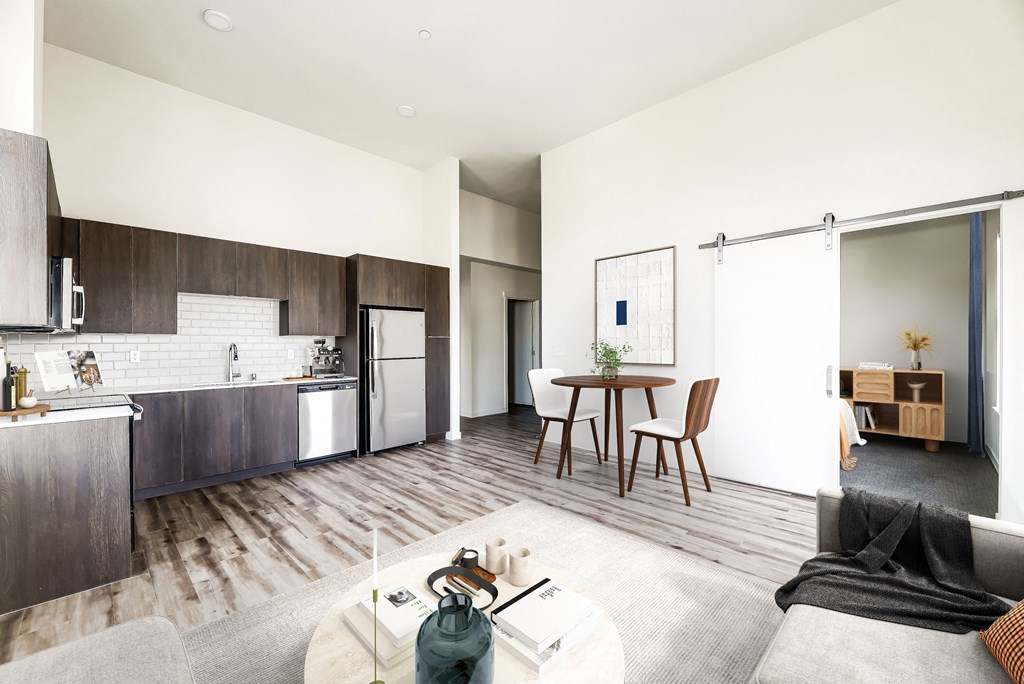 a kitchen and living room with white walls and hardwood floors