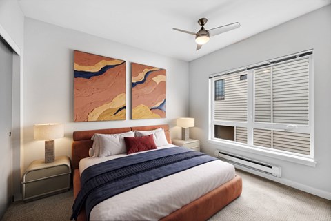A bedroom with a bed, two lamps, and a ceiling fan.