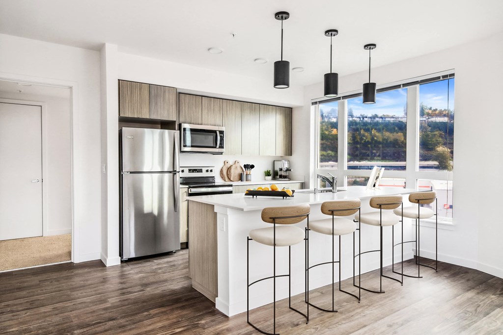 a kitchen with a large island with bar stools and a stainless steel refrigerator