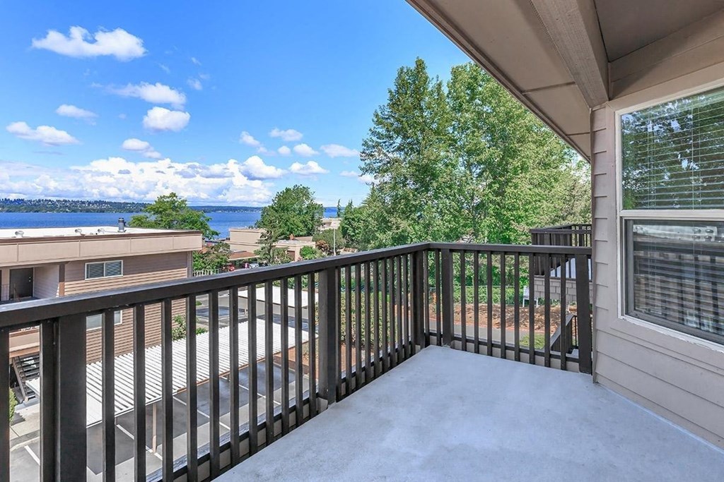a balcony with a view of the water and trees