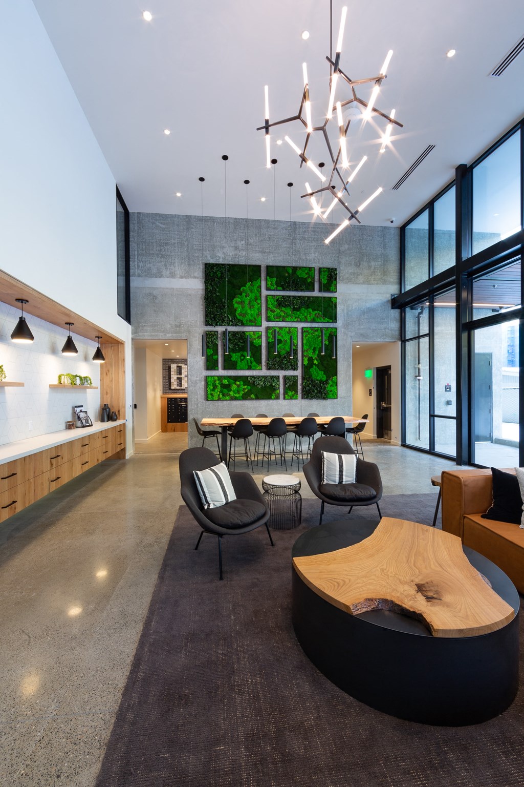 a communal area with a table and chairs and a wall of green plants