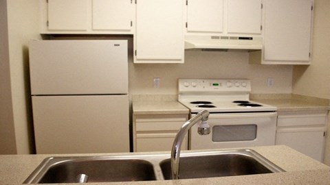 A kitchen with a white stove and white cabinets.