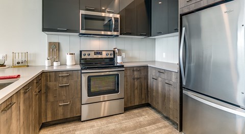 A modern kitchen with a stainless steel refrigerator and wooden cabinets.