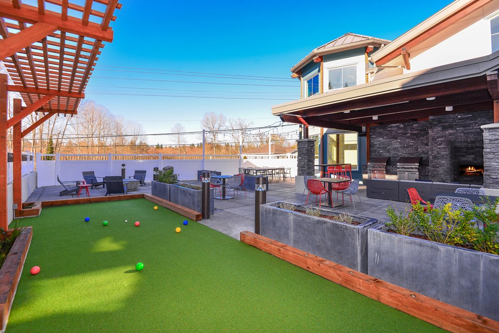 a backyard with a pool and bocce ball court and a patio with chairs