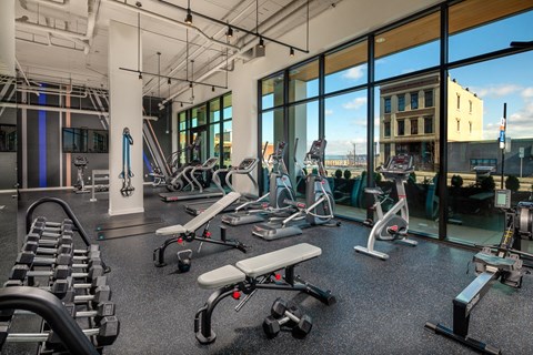 a gym with weights and cardio equipment and windows
