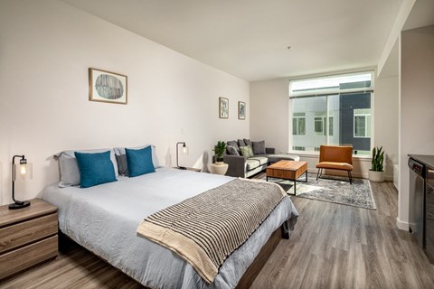 a bedroom with a bed and a couch in a room with a large window