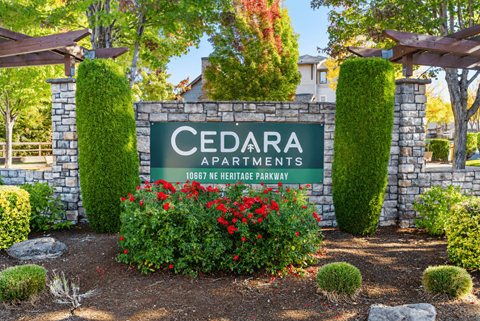 A sign that says Cedara Apartments stands in front of a building.