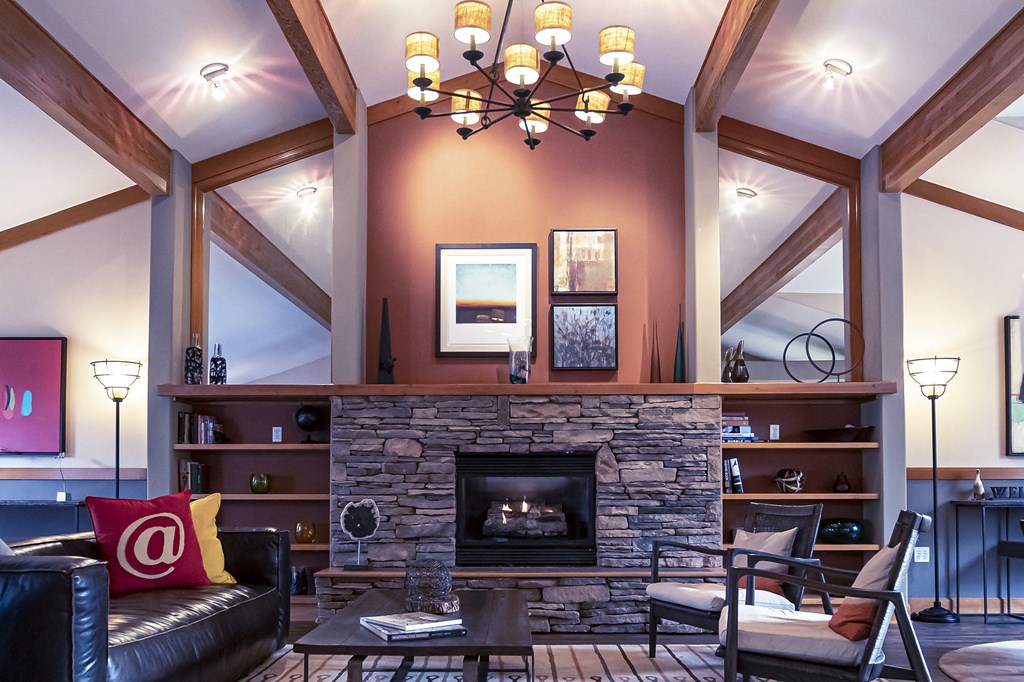 a living room with a stone fireplace and a chandelier
