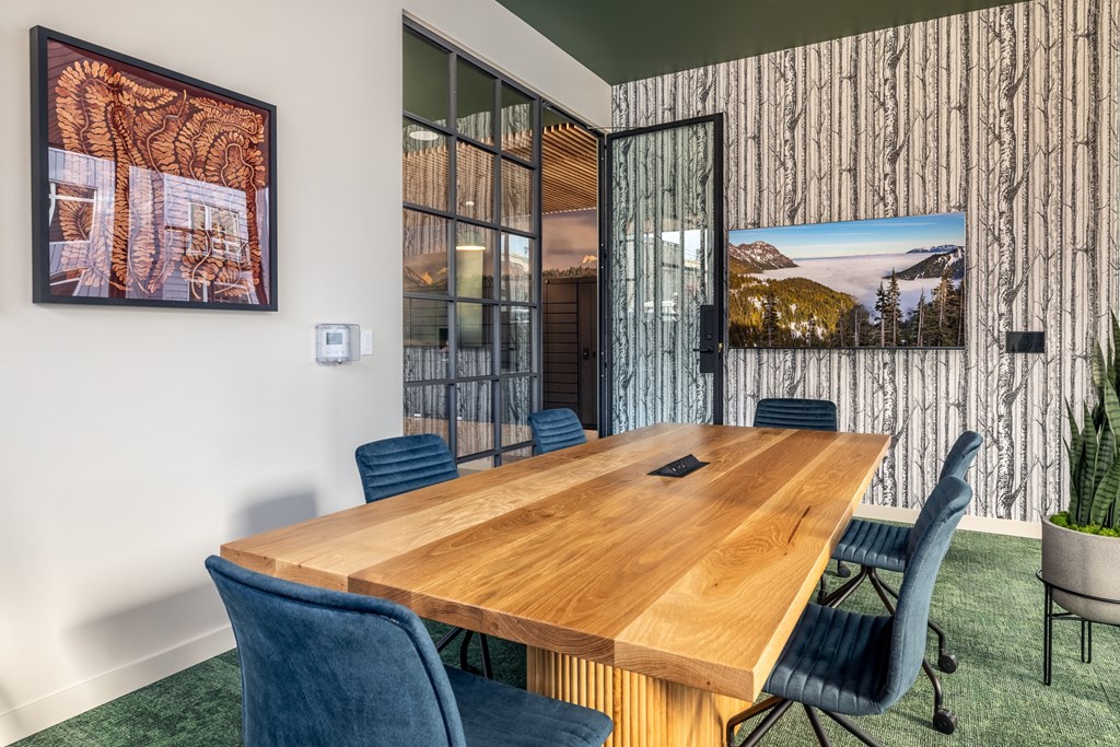 A conference room with a long wooden table surrounded by blue chairs.