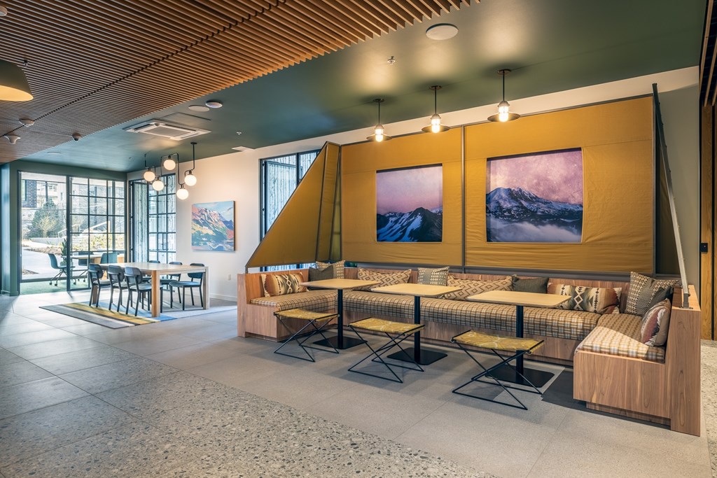 A modern cafe with a wooden ceiling and a large mountain painting on the wall.
