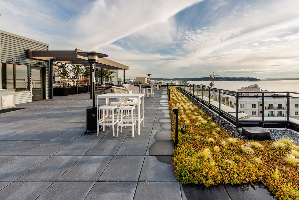 a view of the terrace of the hotel with tables and chairs and a grassy area