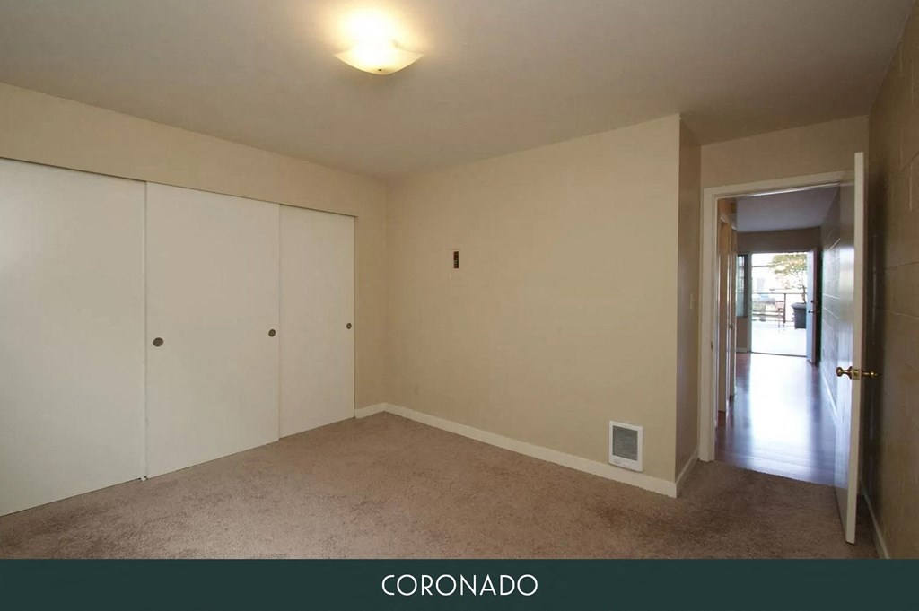 an empty living room with white cabinets and a door to a hallway