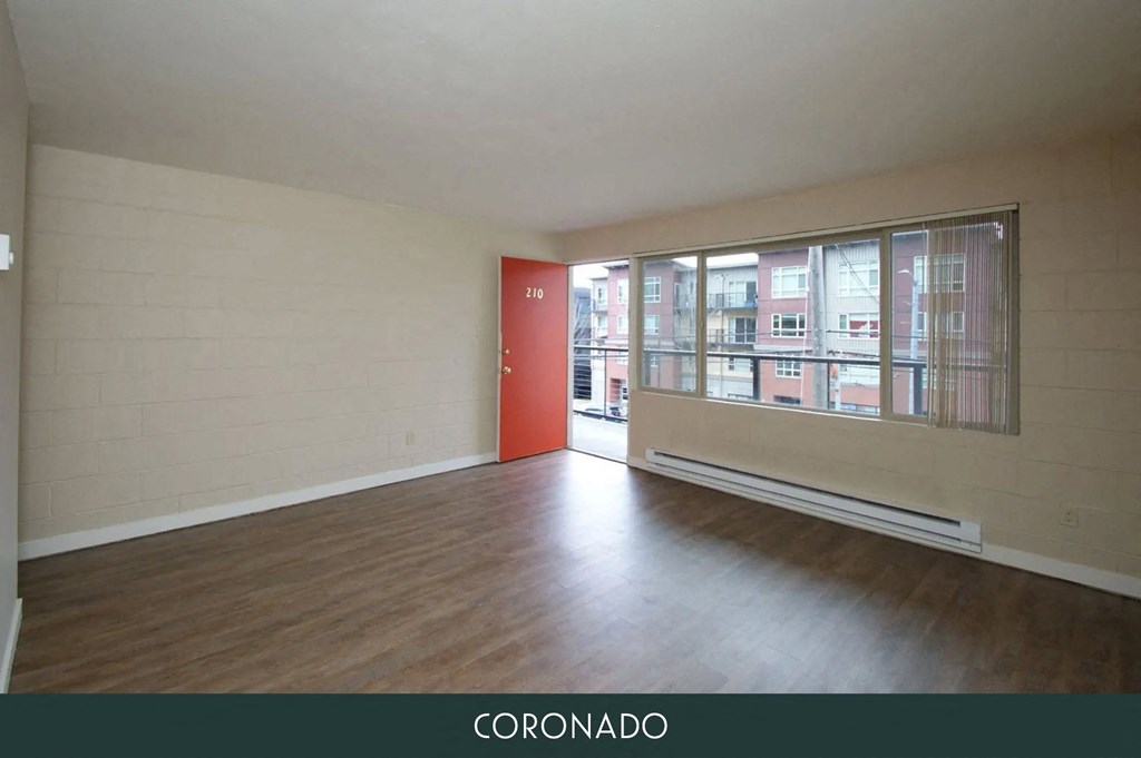 an empty living room with wood floors and a large window