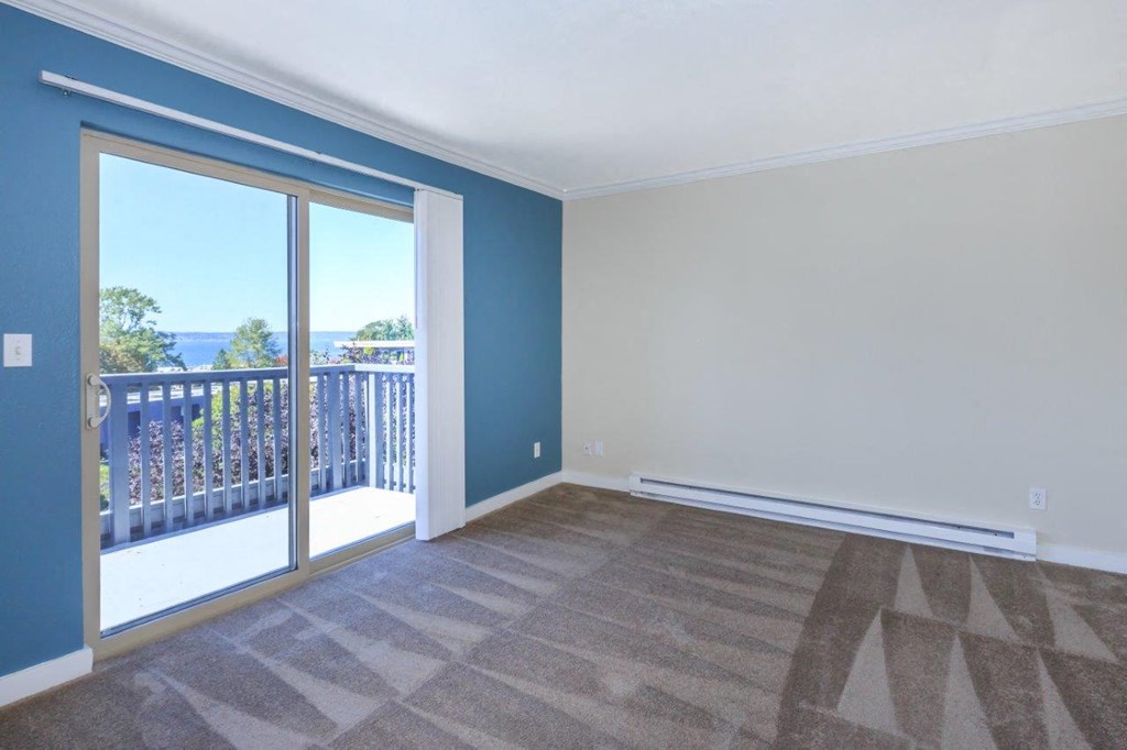 an empty living room with a sliding glass door and a balcony
