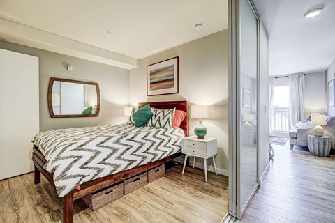 A bedroom with a bed, nightstand, and a mirror on the wall.