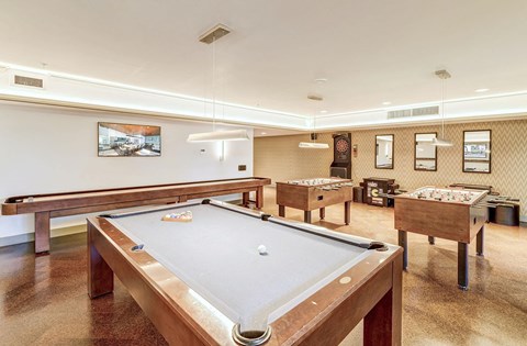 A pool table is in the middle of a room with a picture hanging on the wall.