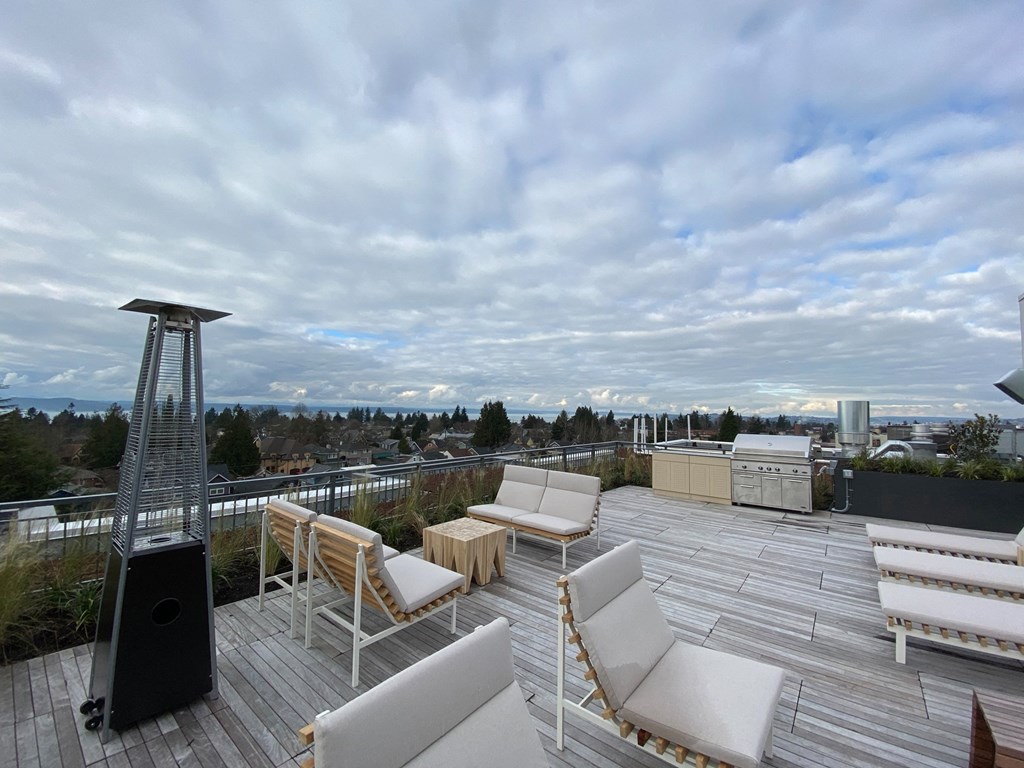 A rooftop patio with white furniture and a speaker.