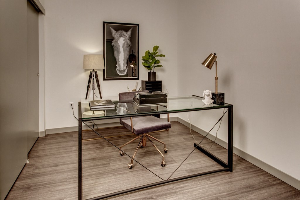 a home office with a glass desk and a chair and a picture of a horse