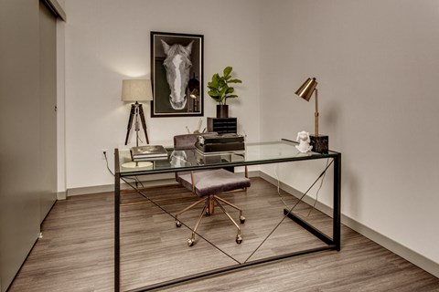 a home office with a glass desk and a chair and a picture of a horse