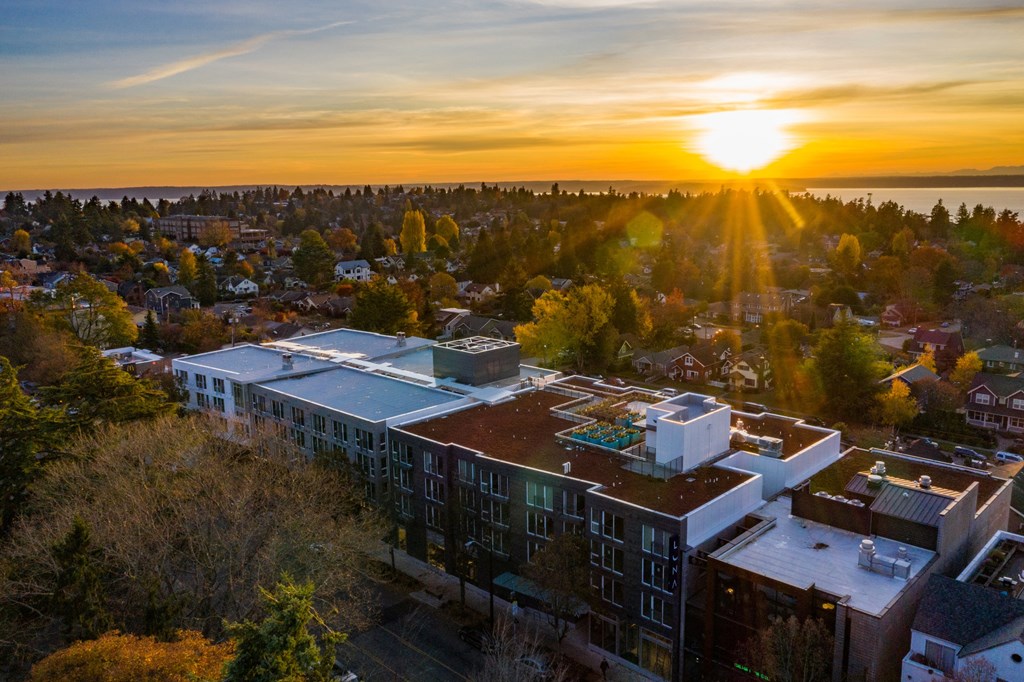 A sunset view of a cityscape with buildings and trees.